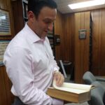 In his and his father's law office, Mike Testa admires a book published in 1919 from the library built by his grandfather, the Honorable late Frank J. Testa.